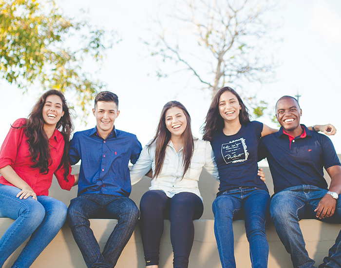 Students sitting together on a bench with their arms around each other.